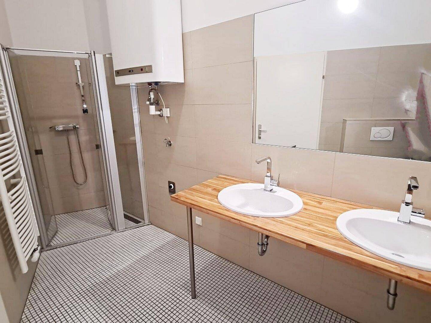 Modernes Badezimmer mit Doppelwaschbecken, begehbarer Dusche und beheiztem Handtuchhalter.