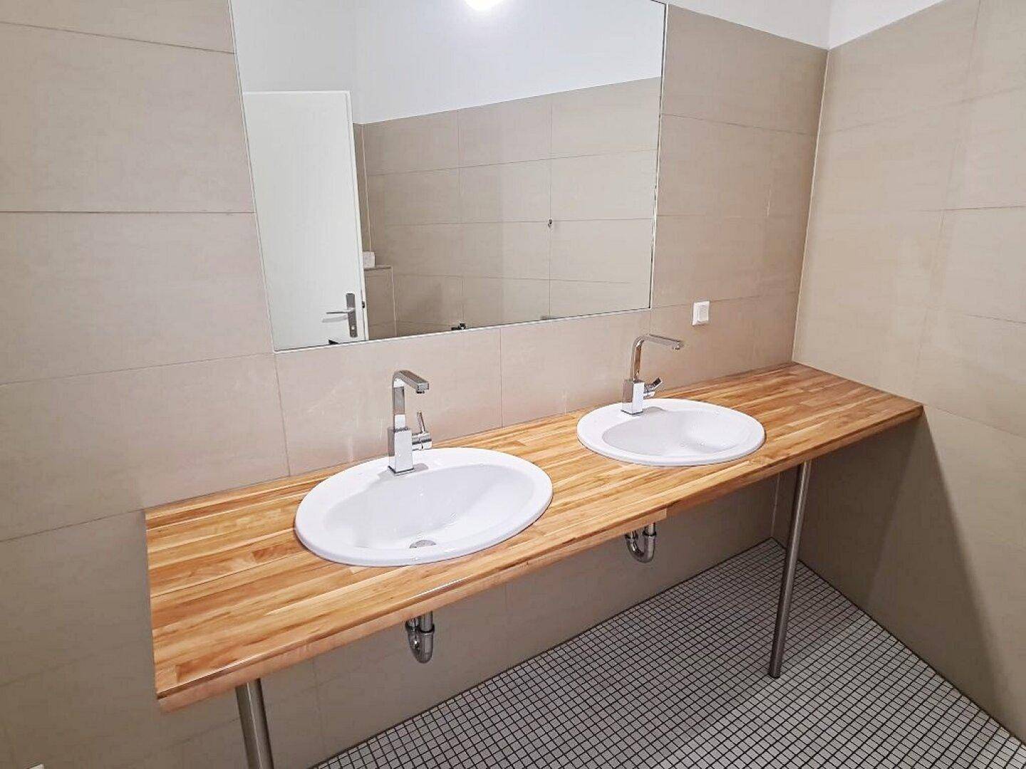 Modernes Badezimmer mit Doppelwaschbecken, Holzwaschtisch und hellen Wandfliesen.