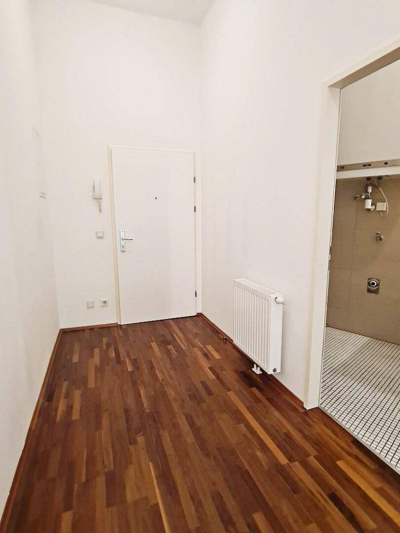 Heller Flur mit Parkettboden und Zugang zum Badezimmer.