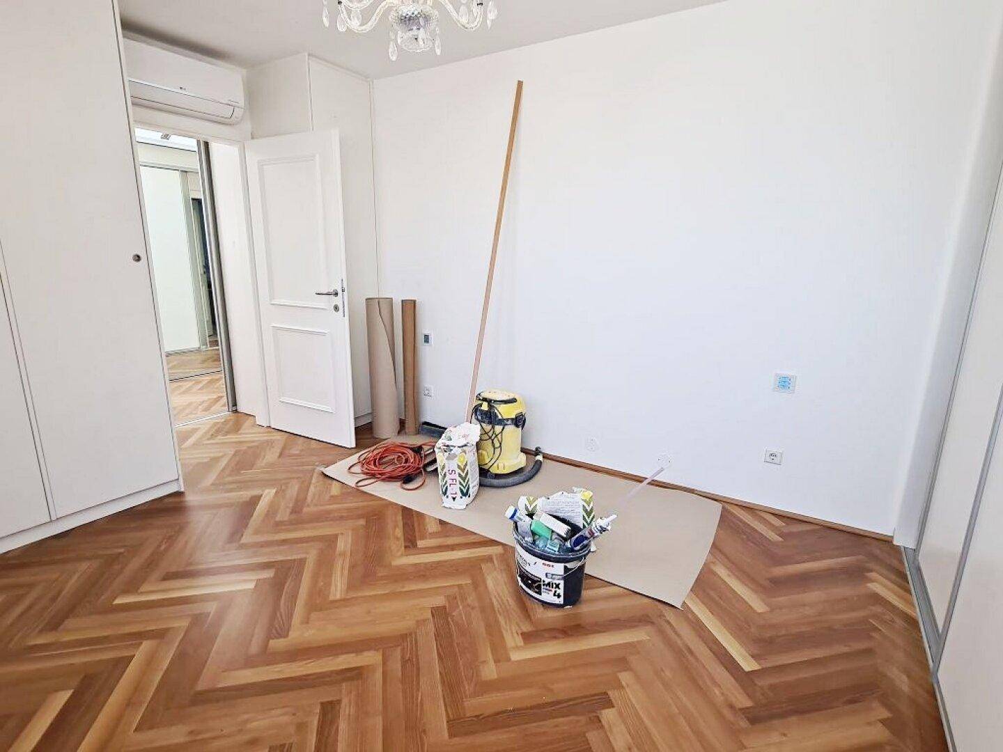 Schlafzimmer mit Parkettboden, Klimaanlage und Zugang zu anderen Bereichen der Wohnung.