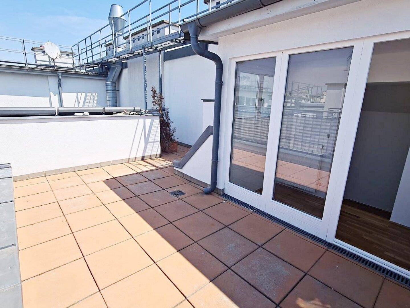 Geräumige Dachterrasse mit Fliesenboden und weitem Blick über die umliegenden Dächer.