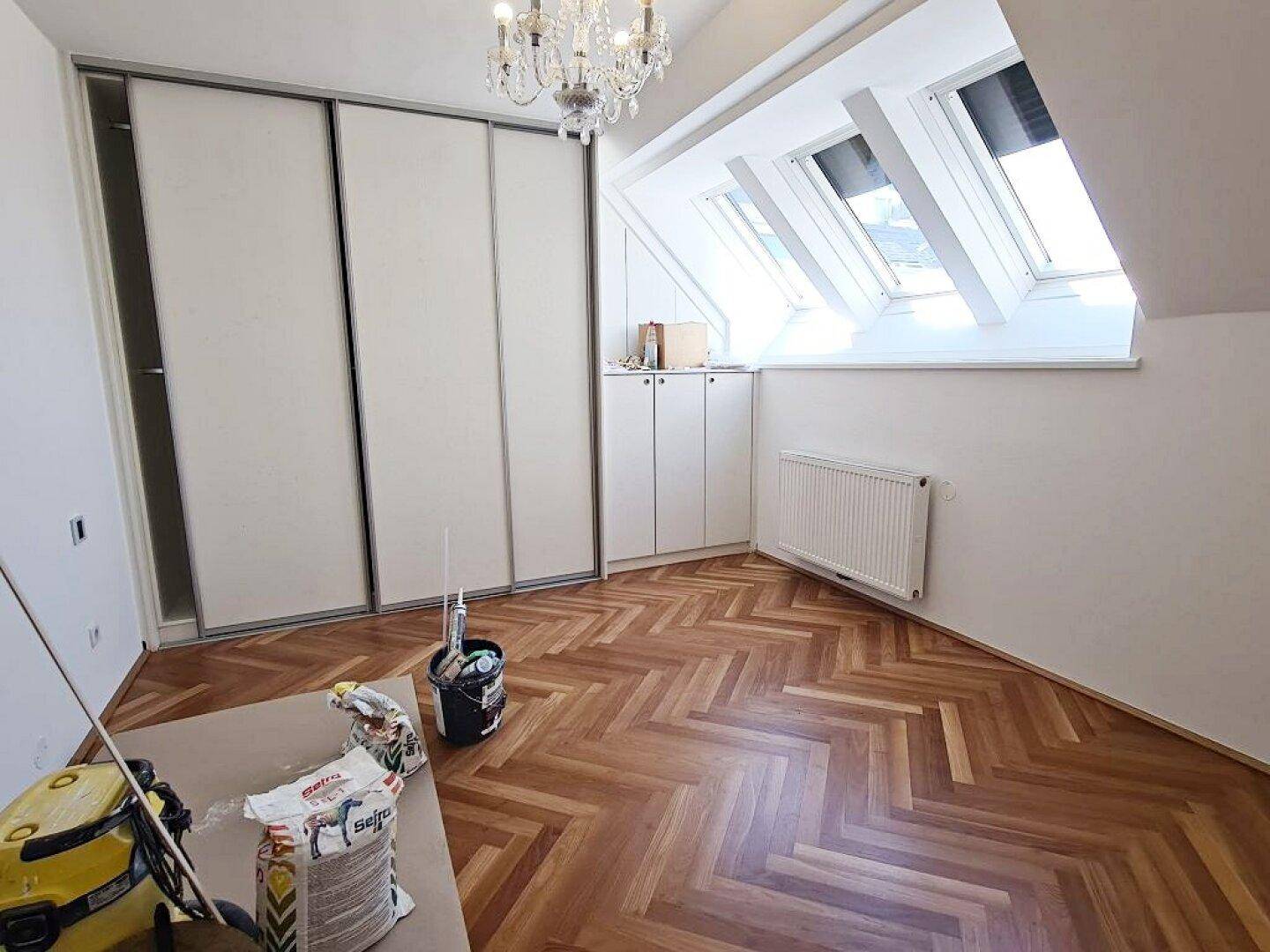 Schlafzimmer mit Fischgrätparkett, Einbauschränken und Dachfenstern, die viel Licht spenden.