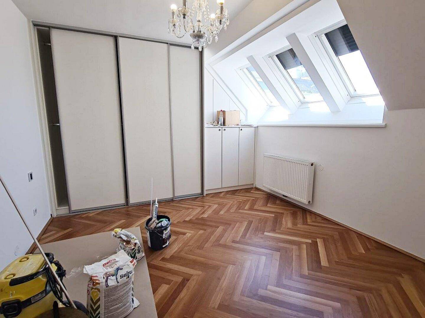 Schlafzimmer mit Fischgrätparkett, Einbauschränken und Dachfenstern, die viel Licht spenden.
