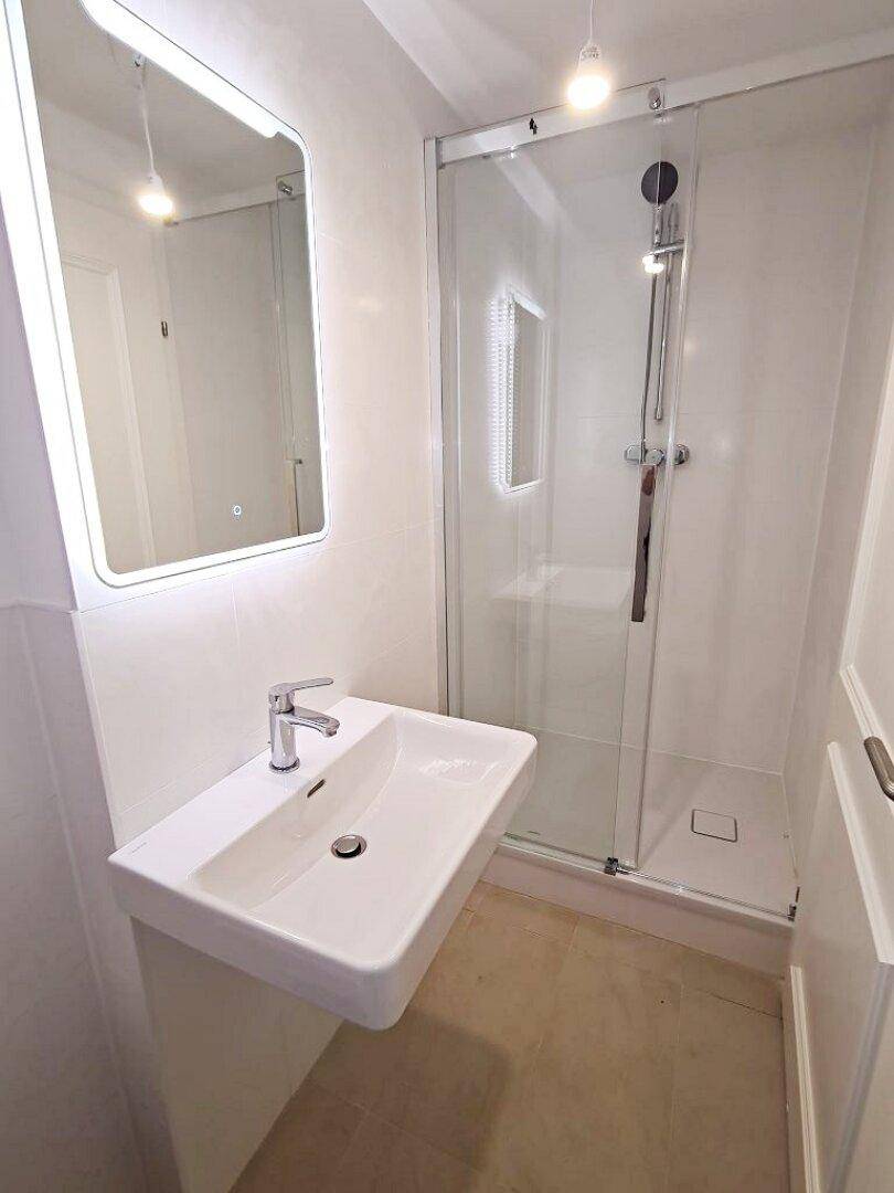 Zeitgemäßes Badezimmer mit schwebendem Waschbecken, beleuchtetem Spiegel und eleganter Glasdusche.