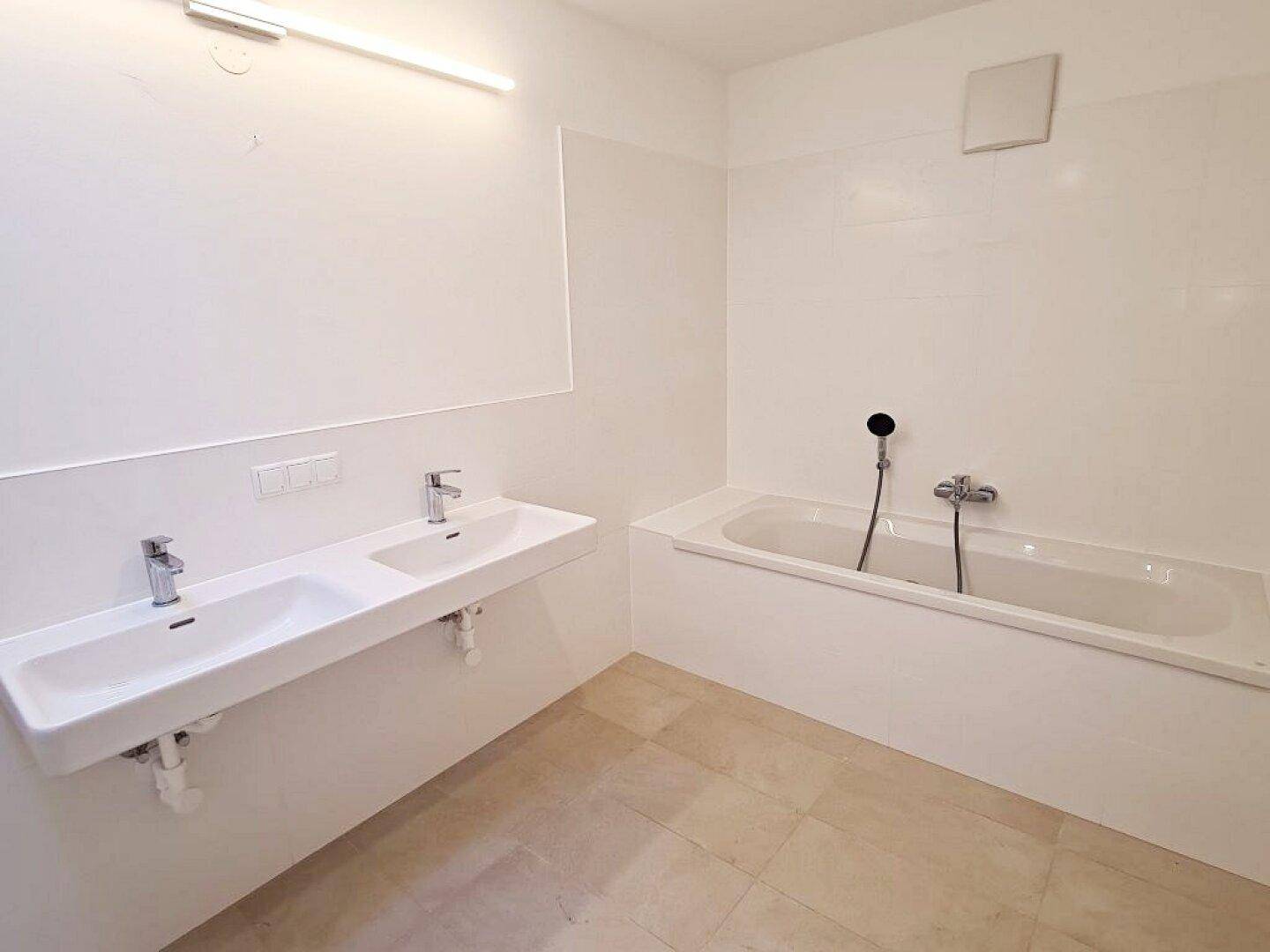 Geräumiges Badezimmer mit Doppelwaschbecken und einer modernen, eingebauten Badewanne.