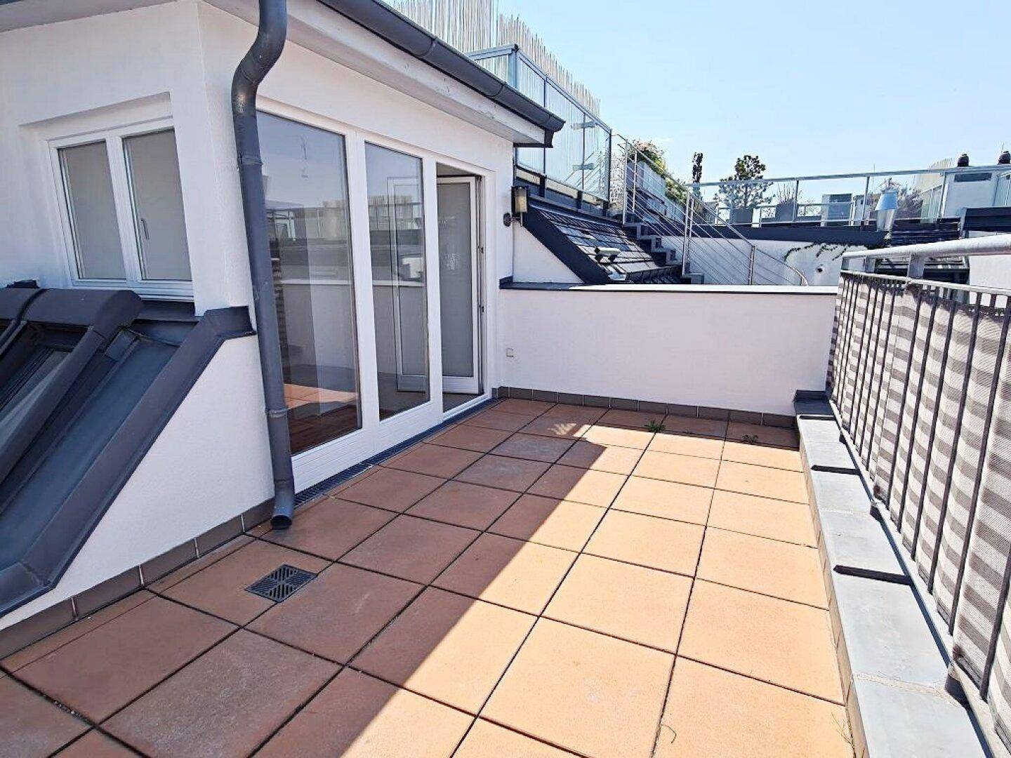 Geräumige Dachterrasse mit Zugang zu Innenräumen und weiteren Dachfenstern, bietet viel Sonnenlicht.