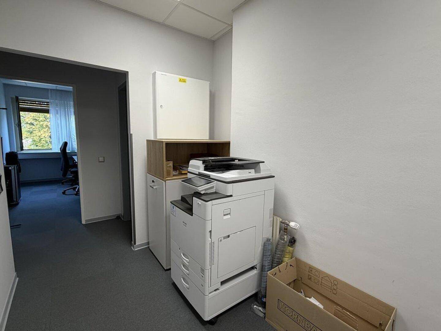 Flurbereich mit einem großen Kopierer und Zugang zu weiteren Büroräumen.