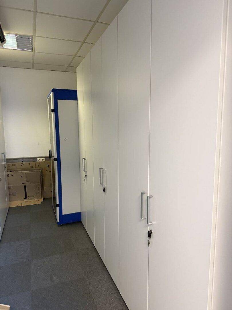 Langer Flur mit weißen Einbauschränken und Teppichboden, ideal für zusätzlichen Stauraum.