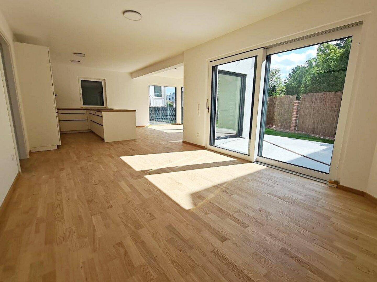 Offener Wohn- und Essbereich mit Holzboden und Schiebetür zur Terrasse.