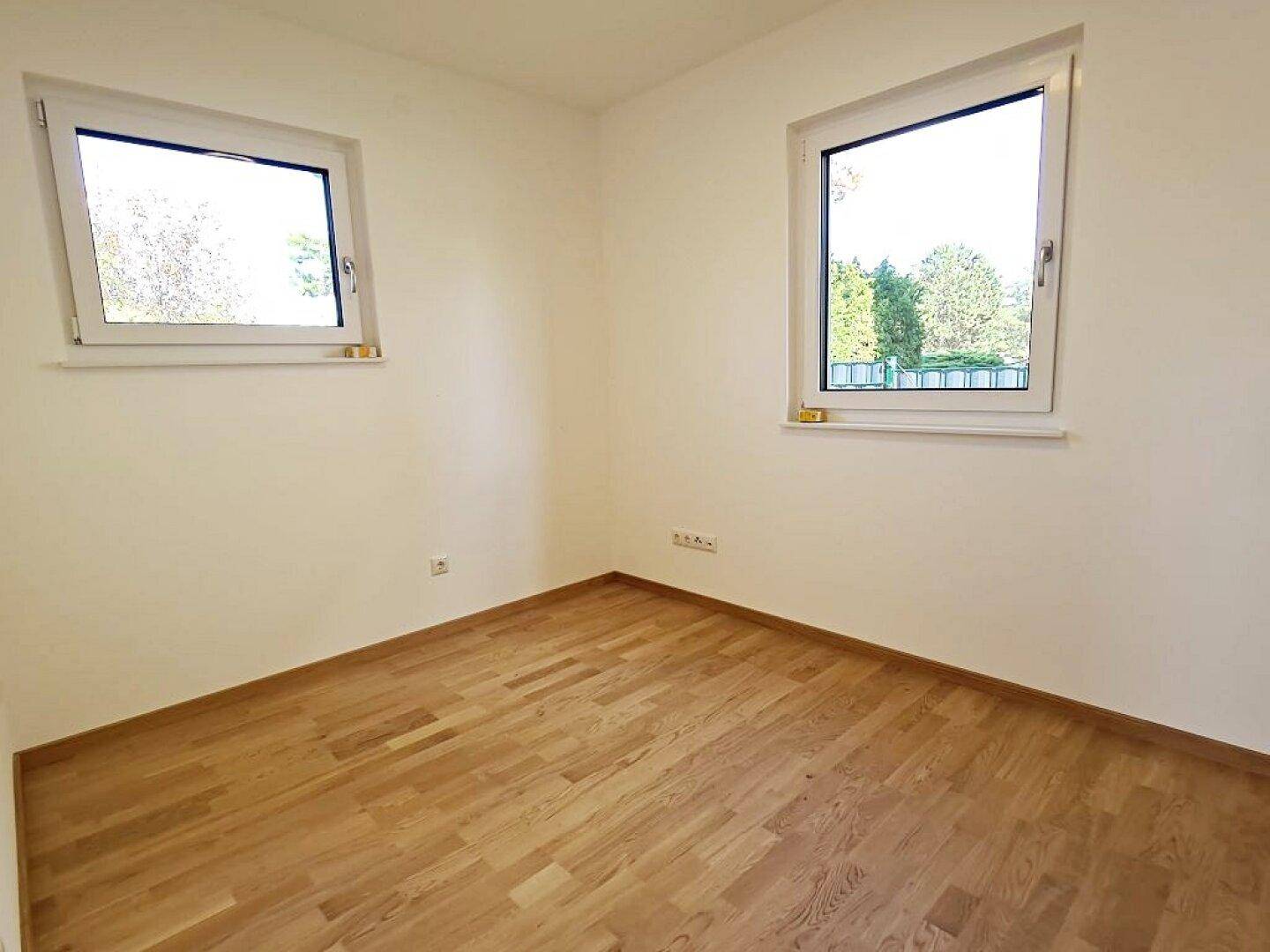 Helles Zimmer mit zwei Fenstern und Parkettboden, ideal als Schlaf- oder Arbeitszimmer nutzbar.