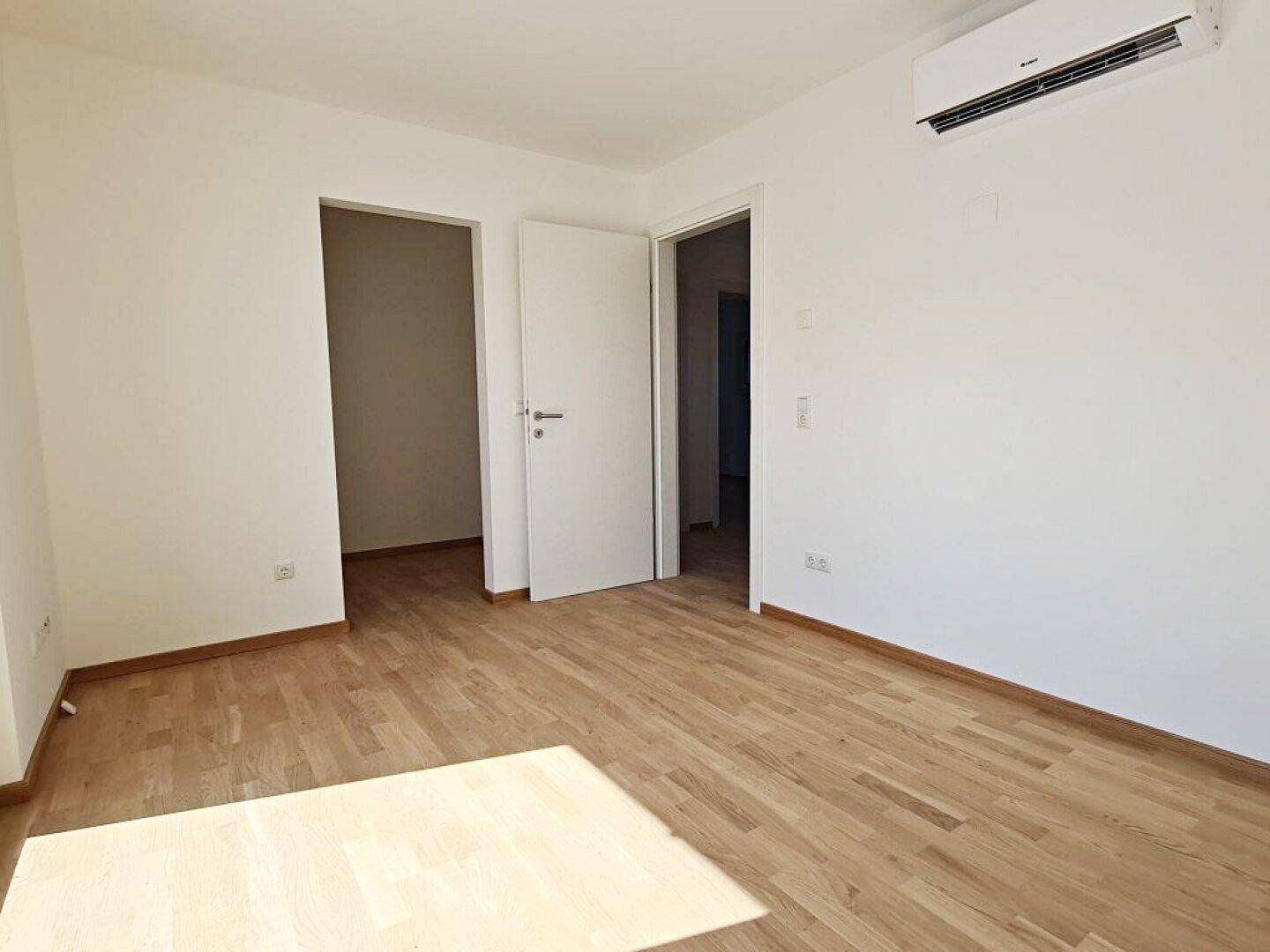Helles Zimmer mit Klimaanlage und Parkettboden, bietet Komfort an warmen Tagen.