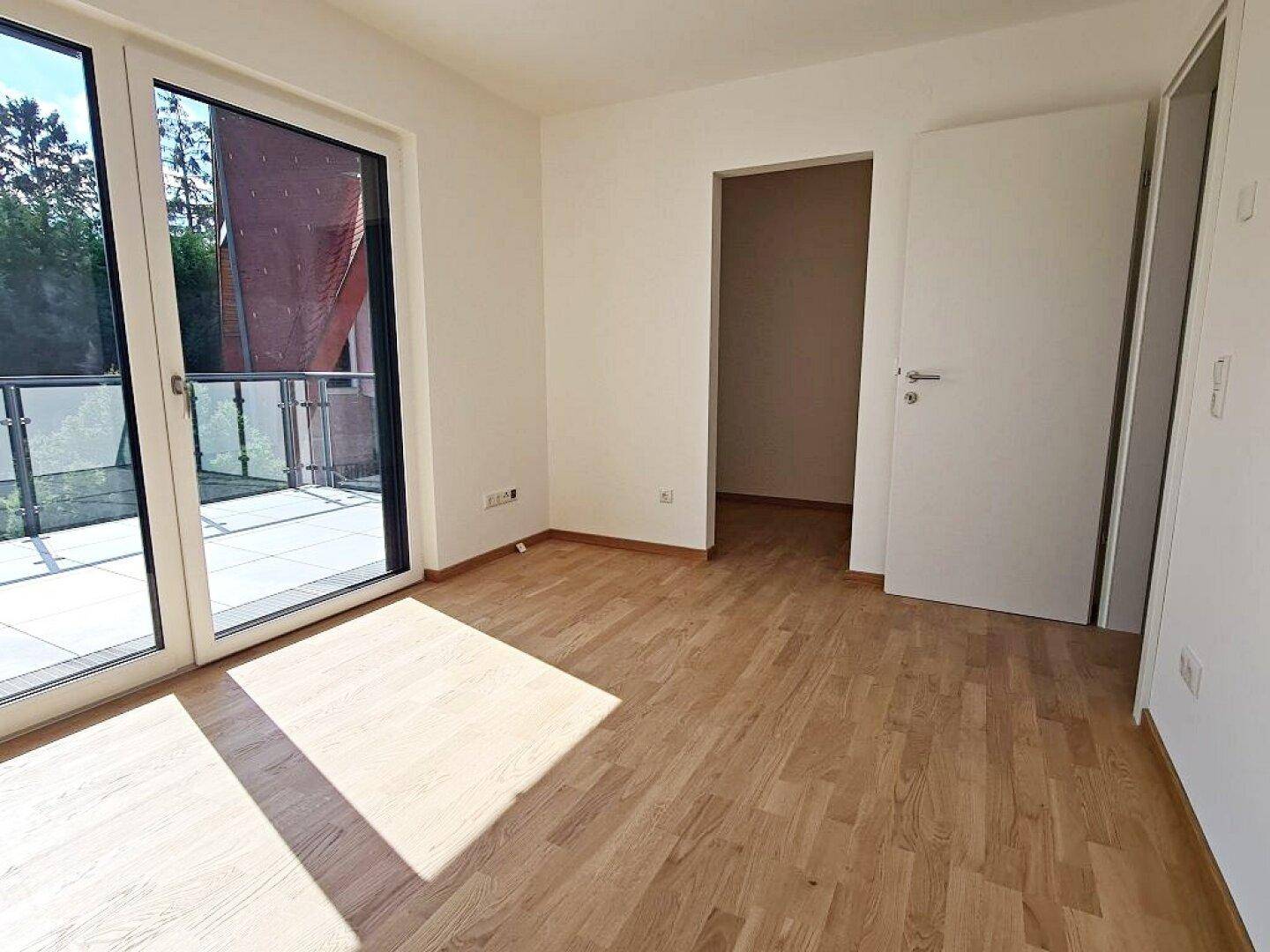 Geräumiges Zimmer mit Parkettboden und Zugang zu einem weiteren Raum, ideal für flexible Nutzung.