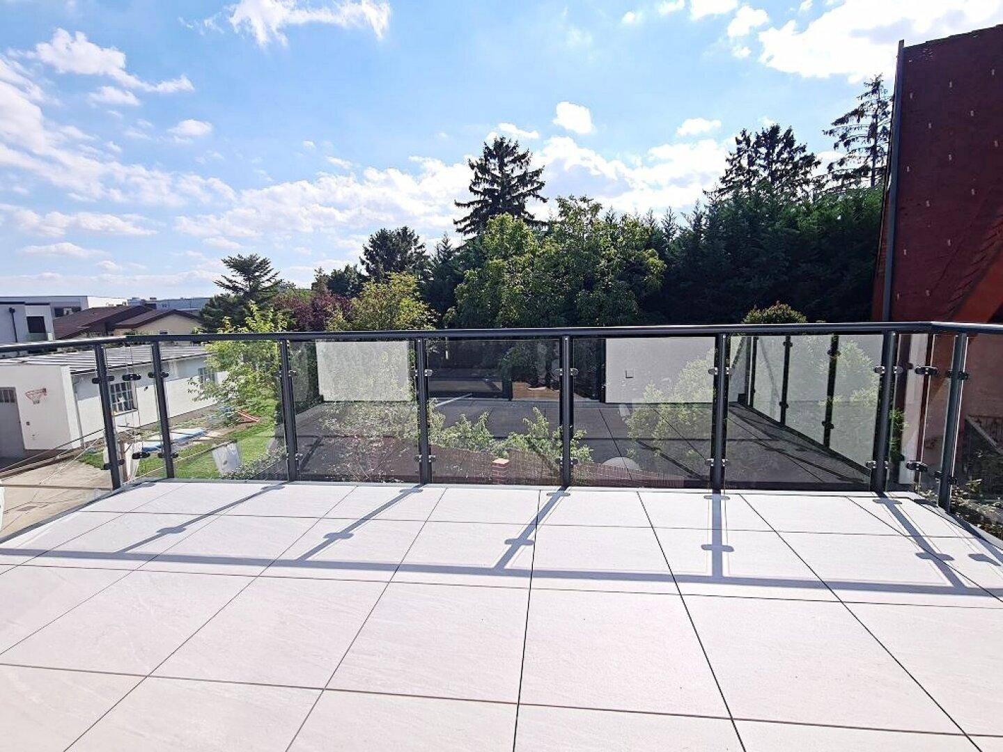 Große Terrasse mit Fliesenboden und weitem Blick ins Grüne, ideal zum Entspannen.
