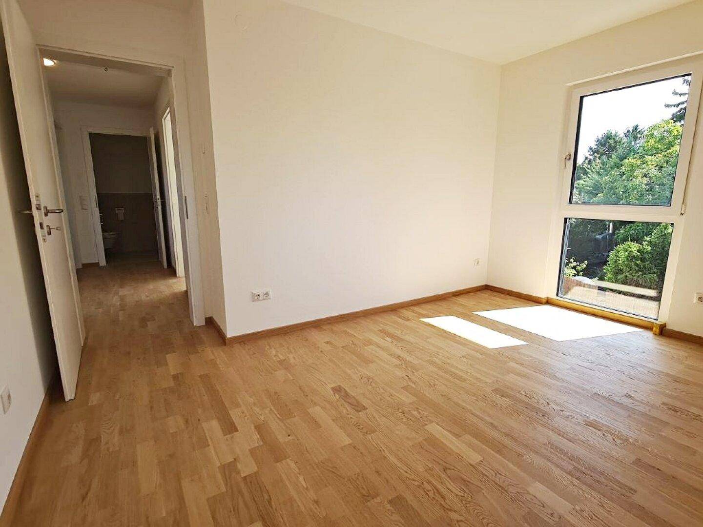 Geräumiges Zimmer mit Parkettboden und Zugang zu einem Flur, ideal als Schlafzimmer.