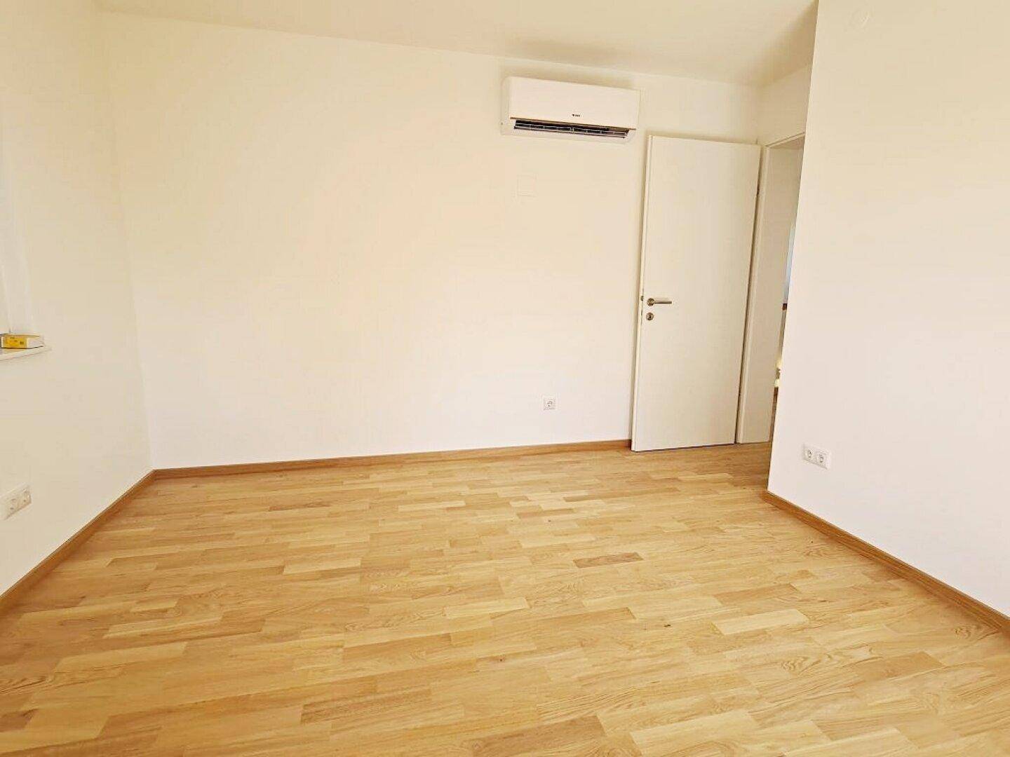 Helles Zimmer mit Klimaanlage und Parkettboden, sorgt für angenehme Raumtemperaturen.