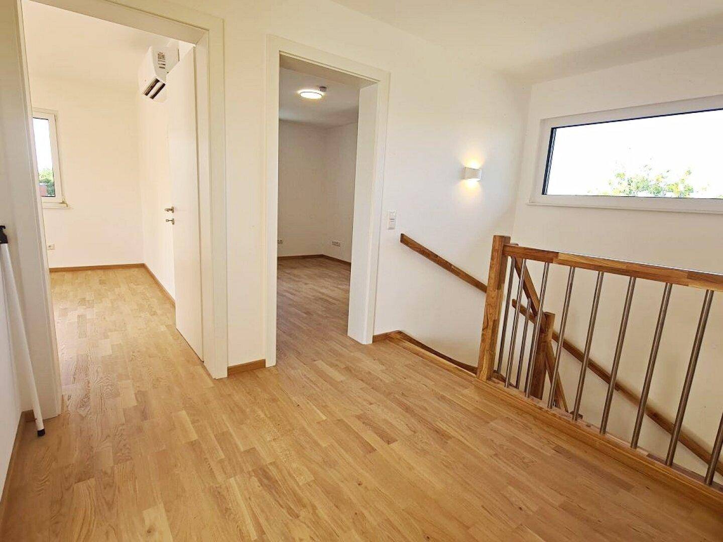 Geräumiger Flur im Obergeschoss mit Holztreppe und Zugängen zu mehreren Zimmern.