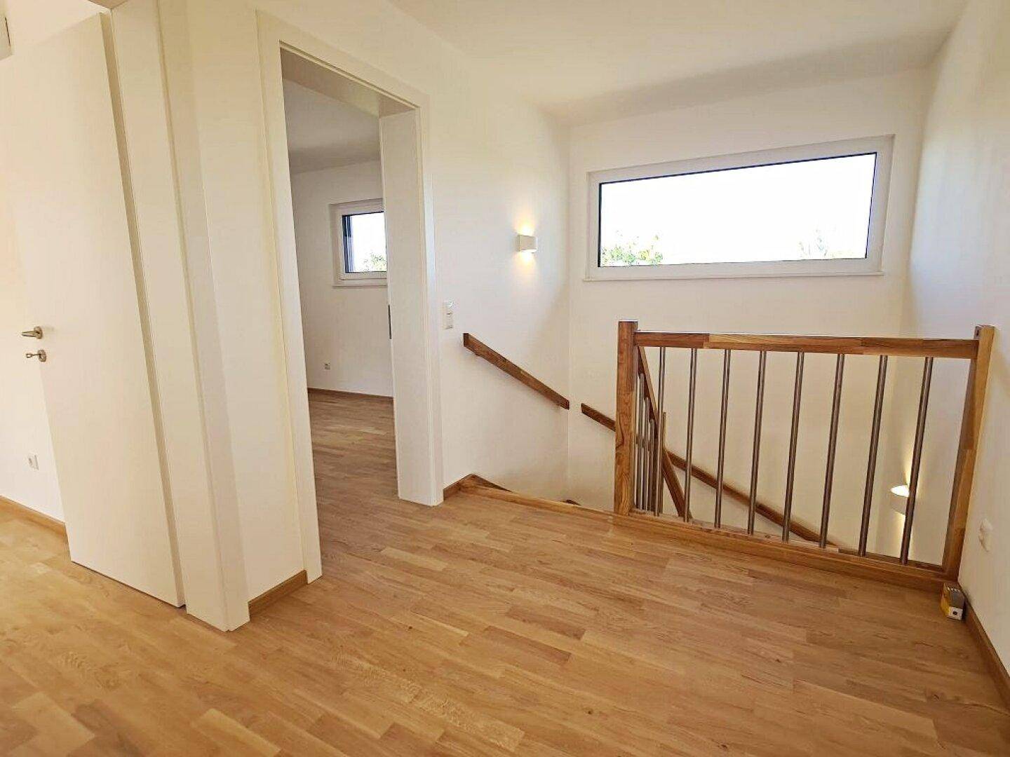 Heller Flur mit Holztreppe und Parkettboden, verbindet die verschiedenen Ebenen des Hauses.