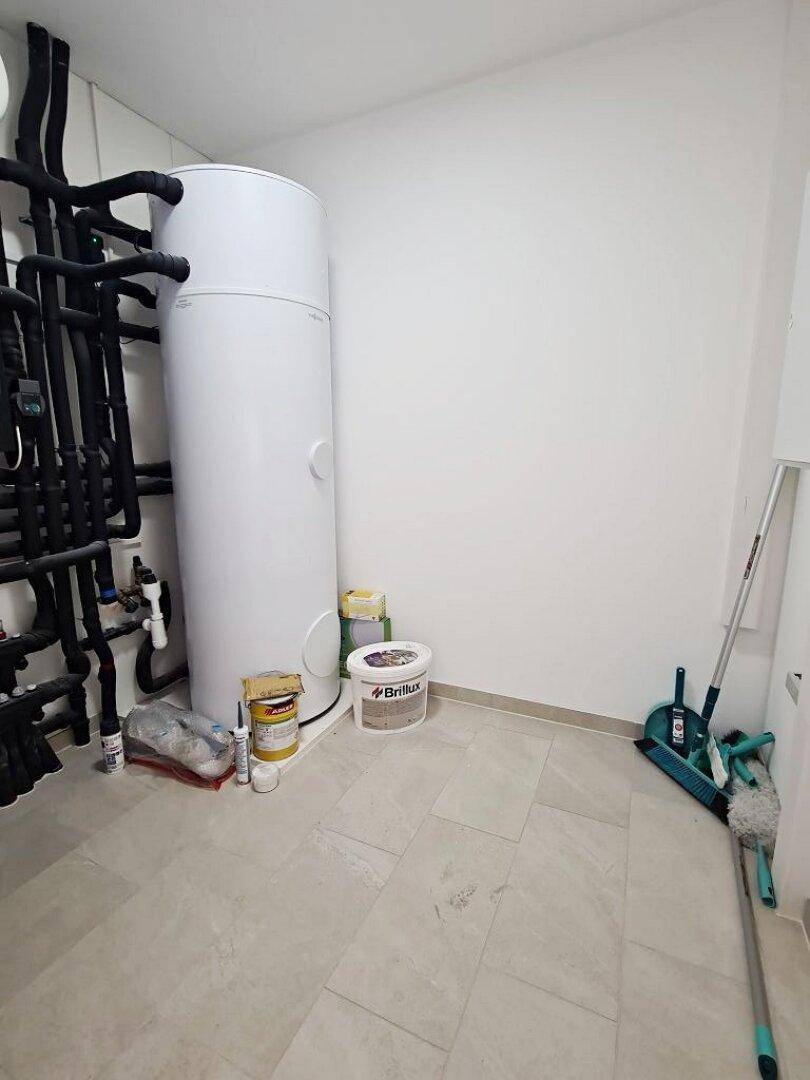 Technikraum mit Warmwasserspeicher und Installationen, ideal für Haustechnik.
