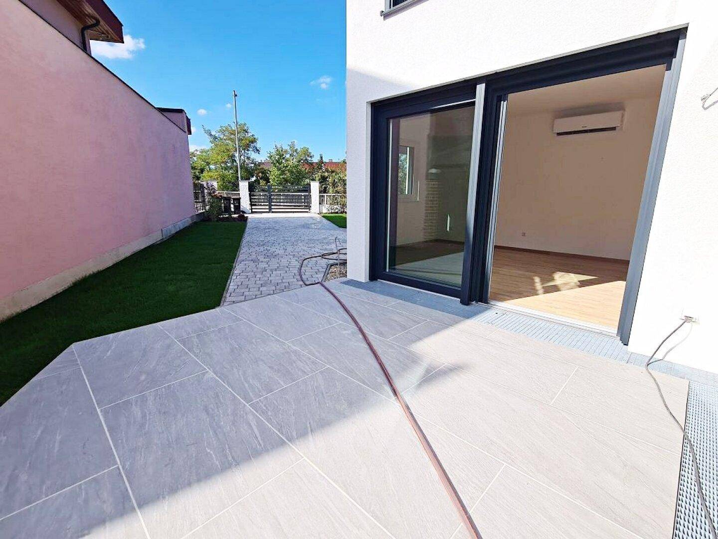 Seitliche Terrasse mit Fliesenboden und Schiebetür zum Innenbereich.