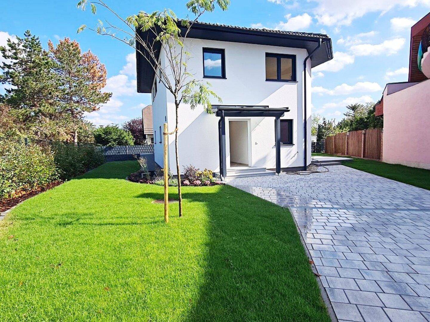 Freistehendes Einfamilienhaus mit moderner Architektur, Vorgarten und gepflasterter Zufahrt.