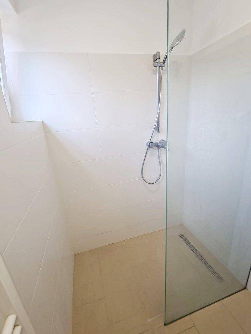 Geräumige, ebenerdige Dusche mit Glasabtrennung und modernen Fliesen im Badezimmer.