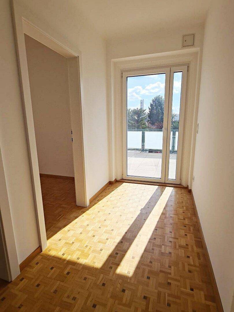 Heller Flur mit Parkettboden und direktem Zugang zu einer sonnigen Terrasse.