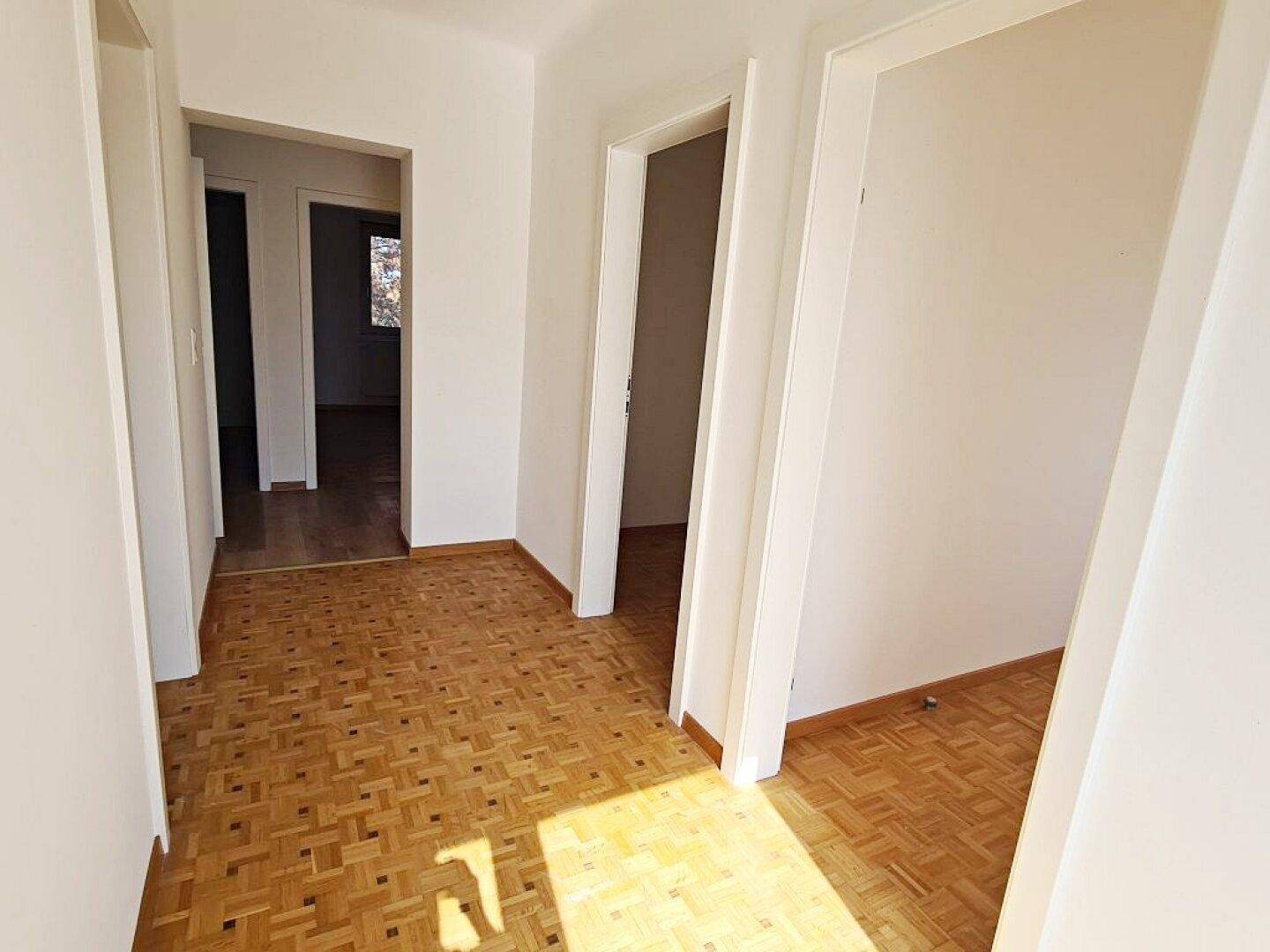 Geräumiger Flur mit Parkettboden, der zu mehreren Zimmern führt und viel Tageslicht erhält.