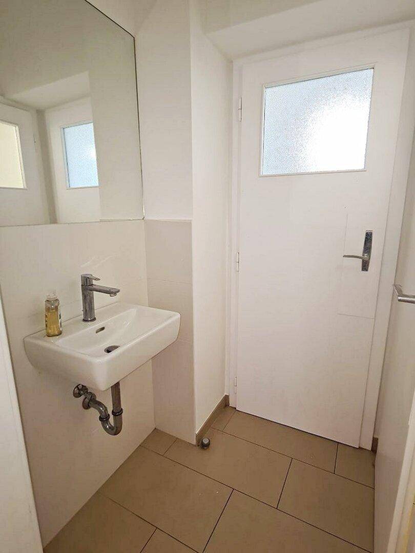 Kleines Gäste-WC mit Waschbecken, Spiegel und Fenster, ideal für Besucher.