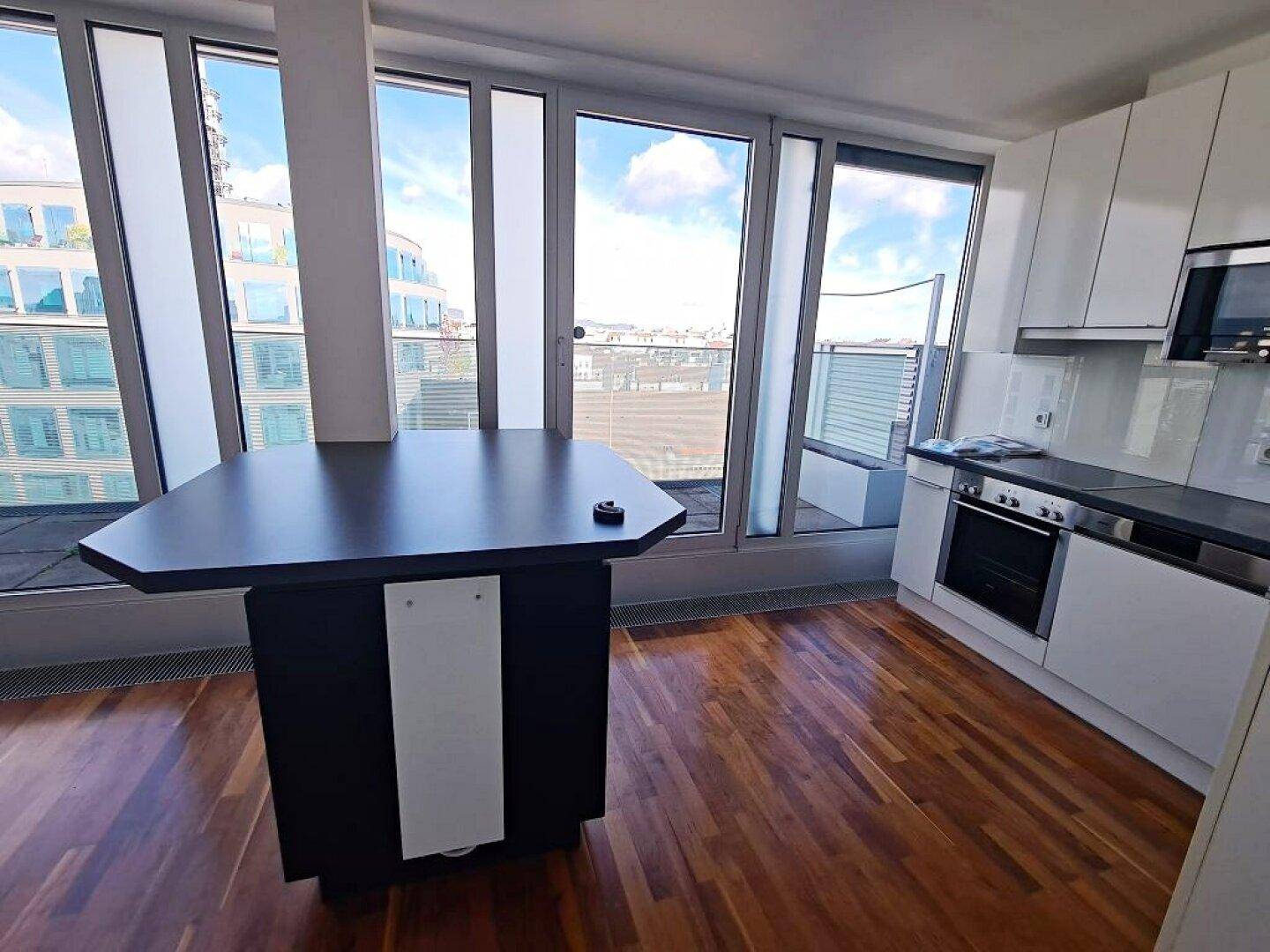 Moderne Küche mit Kücheninsel und Blick durch große Fenster auf die Stadtlandschaft.