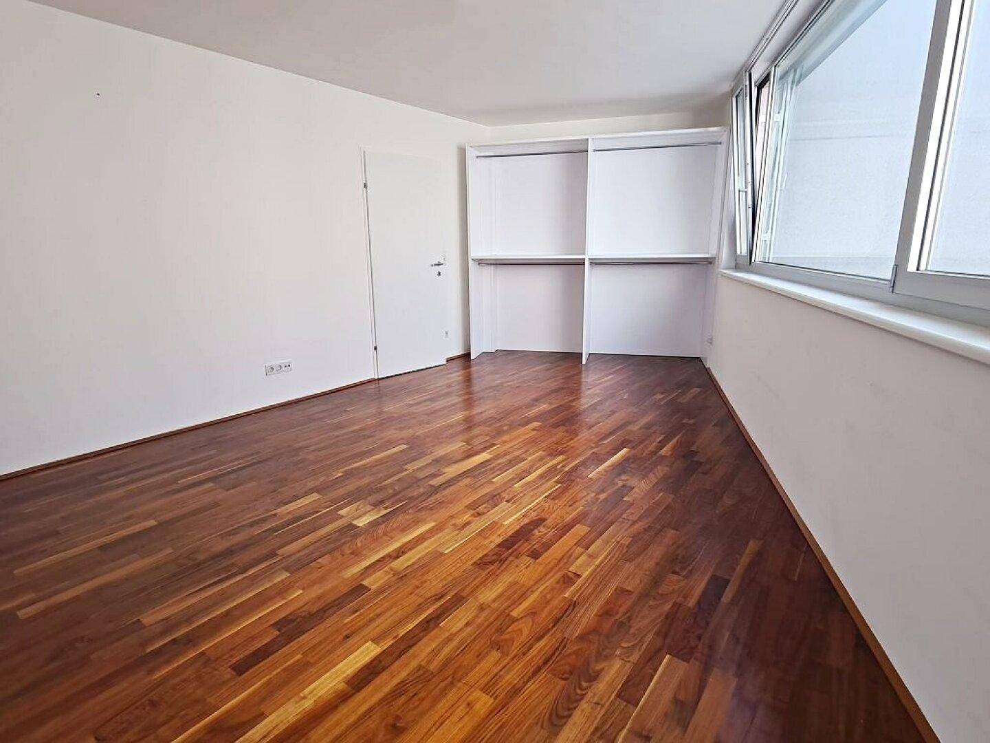 Geräumiges Zimmer mit Einbauschränken und großen Fenstern, bereit zur Einrichtung.