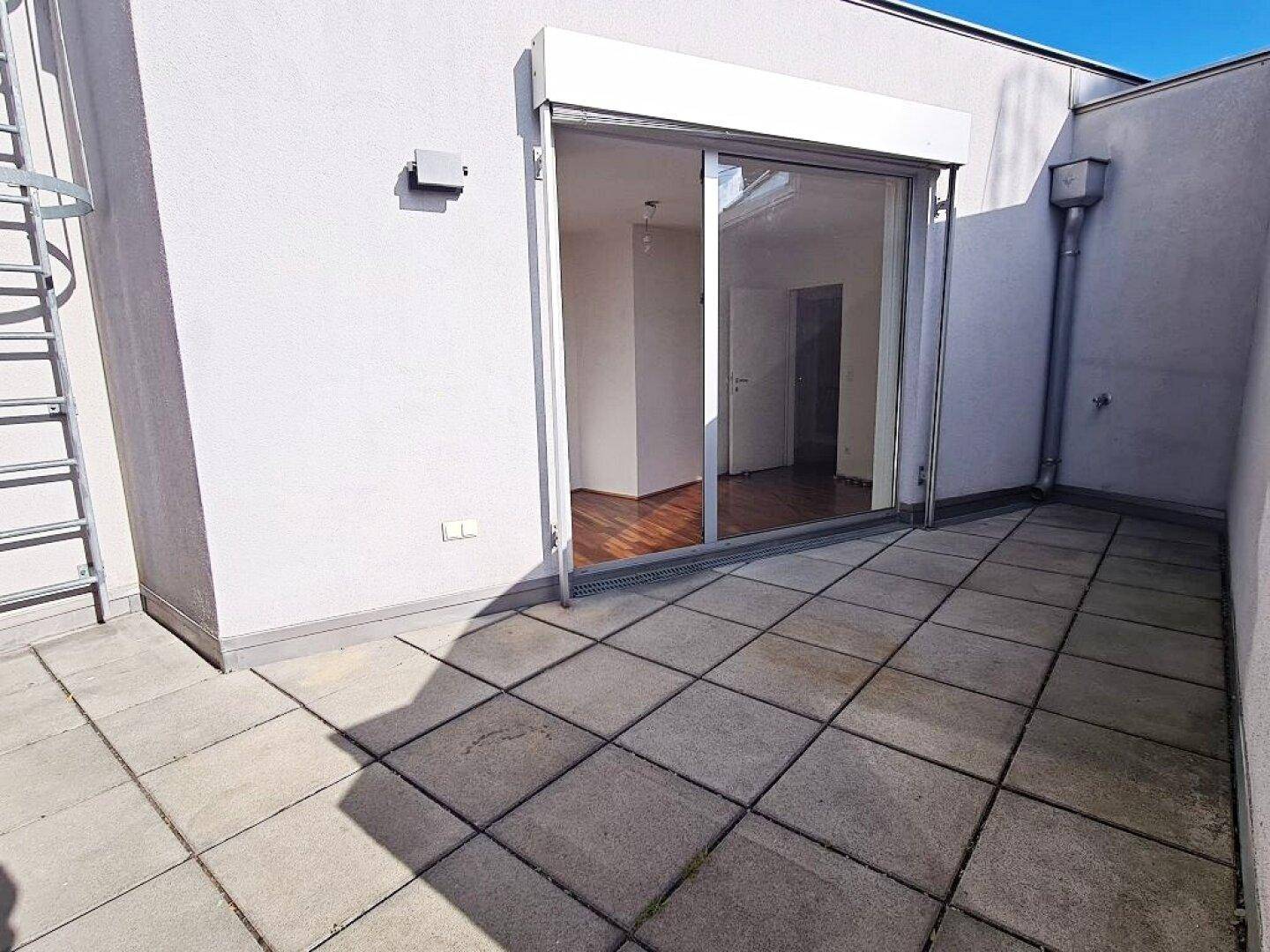 Geräumige Dachterrasse mit Schiebetürzugang zum Innenbereich und Stadtblick.
