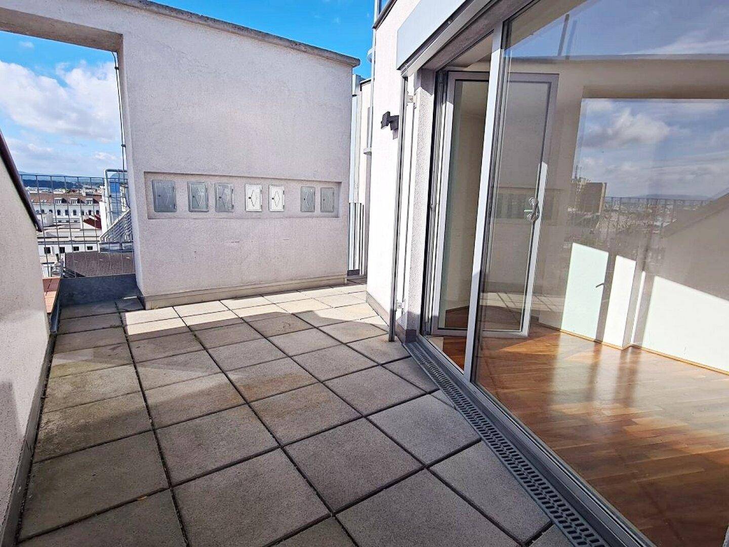 Große Dachterrasse mit Fliesenboden und weitem Blick über die Stadt.