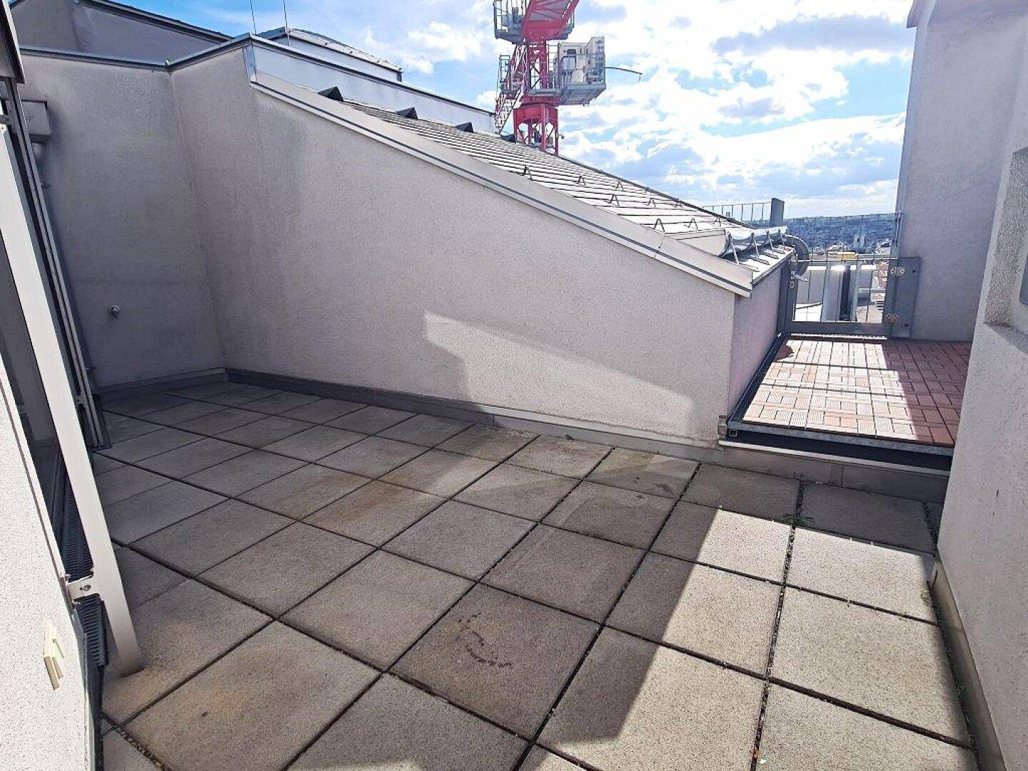 Weitläufige Dachterrasse mit Fliesenboden und Blick auf die umliegende Bebauung.