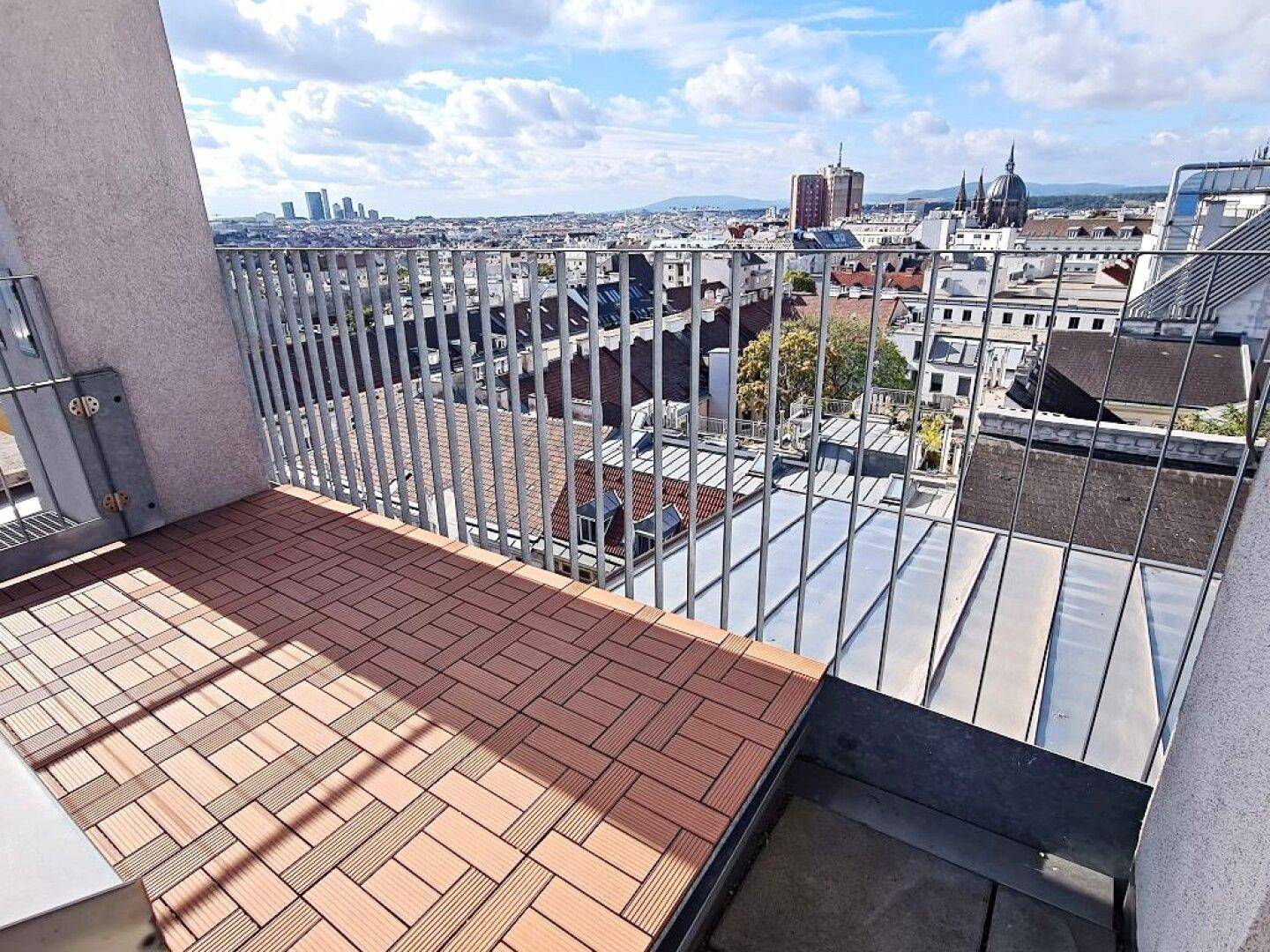 Kleiner Balkon mit Holzdielen und Panoramablick über die Stadt.