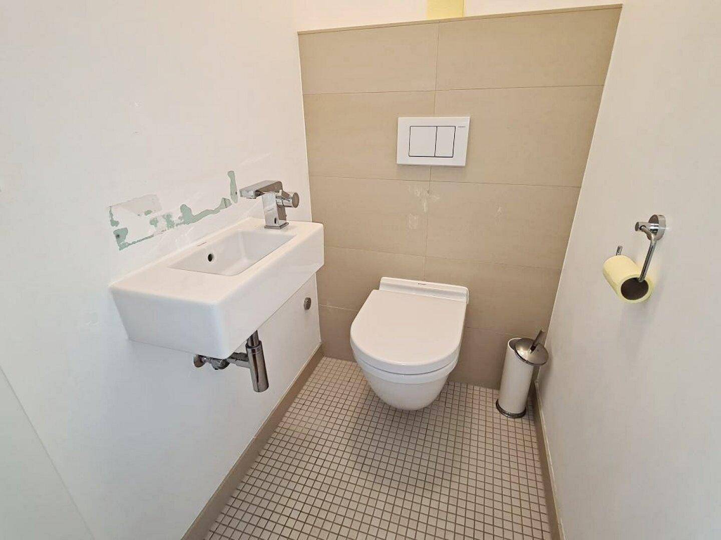 Separates Gäste-WC mit wandhängender Toilette und kleinem Waschbecken.