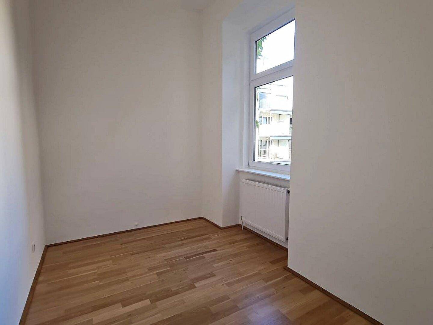 Kleineres Zimmer mit Parkettboden und einem Fenster, geeignet als Schlafzimmer oder Arbeitszimmer.