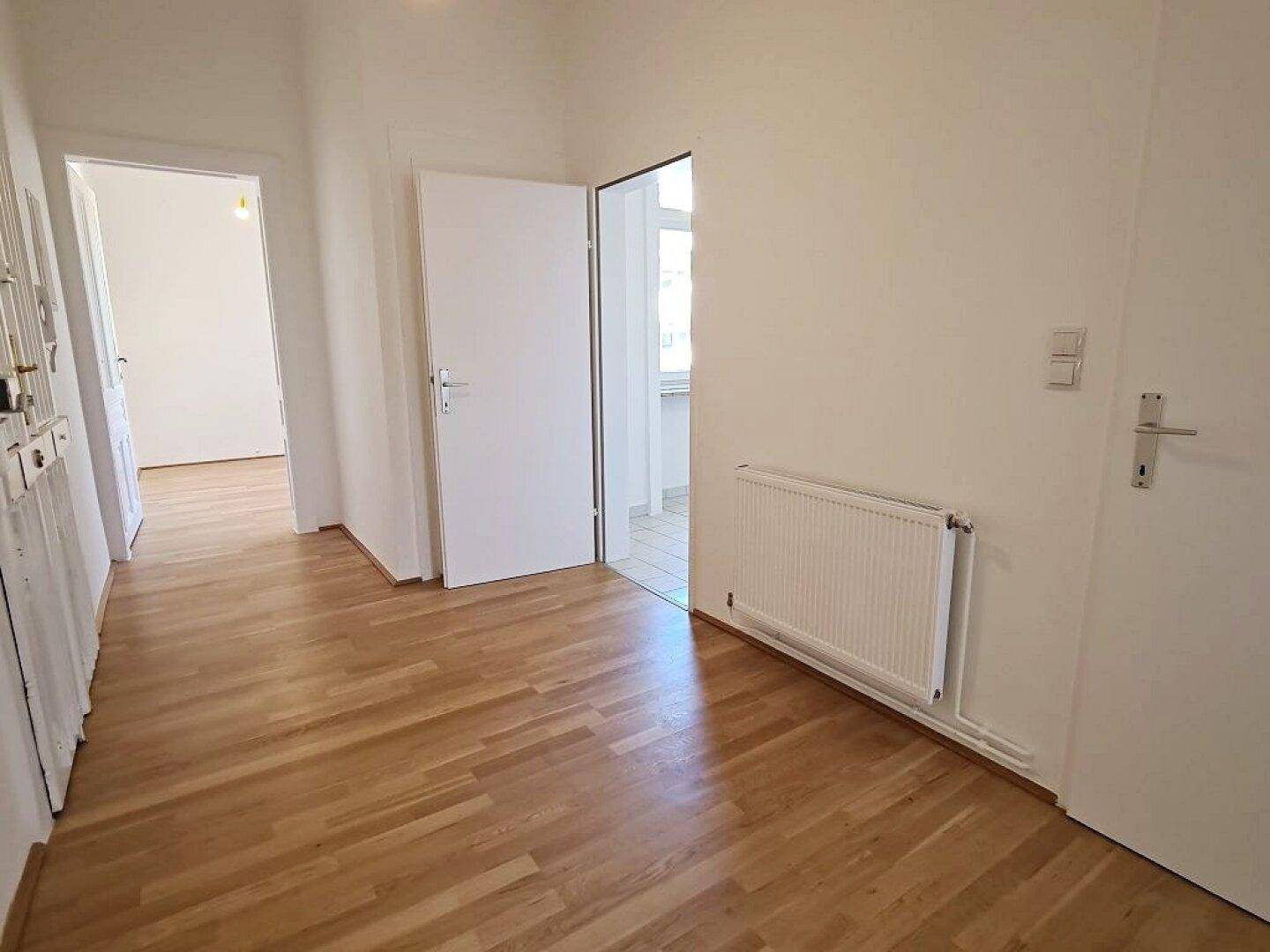 Heller Flur mit Parkettboden und mehreren Türen, die zu den verschiedenen Räumen führen.