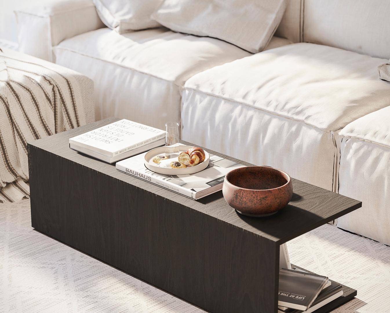 Detailaufnahme eines modernen Couchtisches mit Büchern und Dekoration vor einem bequemen Sofa.
