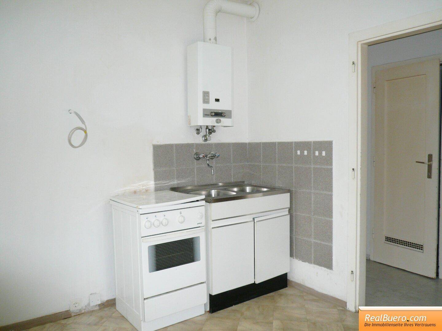 Funktionale Küchenzeile mit Spülbecken, Elektroherd und Warmwasserbereiter, ideal für kleine Wohnungen.