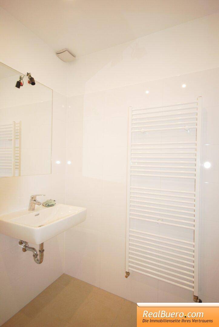 Badezimmer mit Waschbecken, Spiegel und einem praktischen beheizten Handtuchhalter.