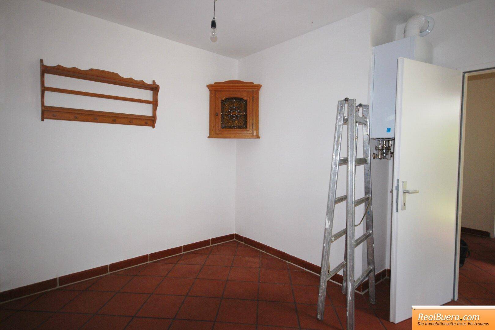 Kleiner Abstellraum mit Fliesenboden, einem Wandschrank und einer Leiter.