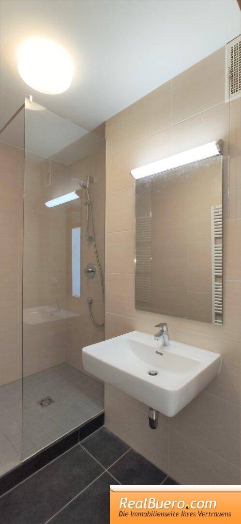 Modernes Badezimmer mit ebenerdiger Dusche, Einzelwaschbecken und praktischem Handtuchheizkörper.