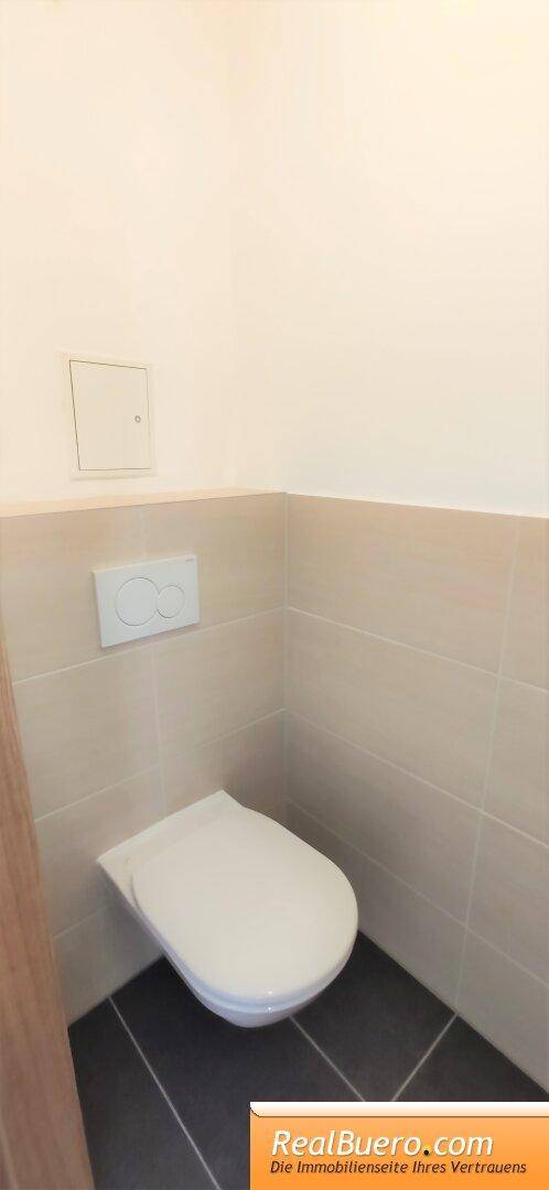 Separates Gäste-WC mit wandhängender Toilette und modernen Fliesen, funktional und sauber.