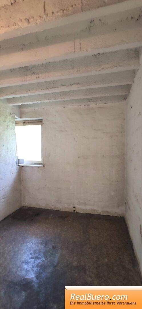 Unausgebauter Kellerraum mit kleinem Fenster und Betonboden, ideal als Stauraum.