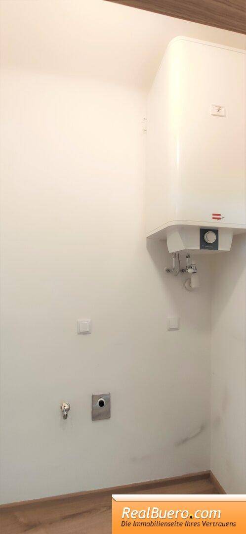 Kleiner Hauswirtschaftsraum mit Warmwasserbereiter und Anschlüssen für Waschmaschine.
