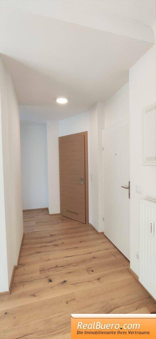 Heller Flur mit Holzboden und Zugang zu verschiedenen Räumen der Wohnung.