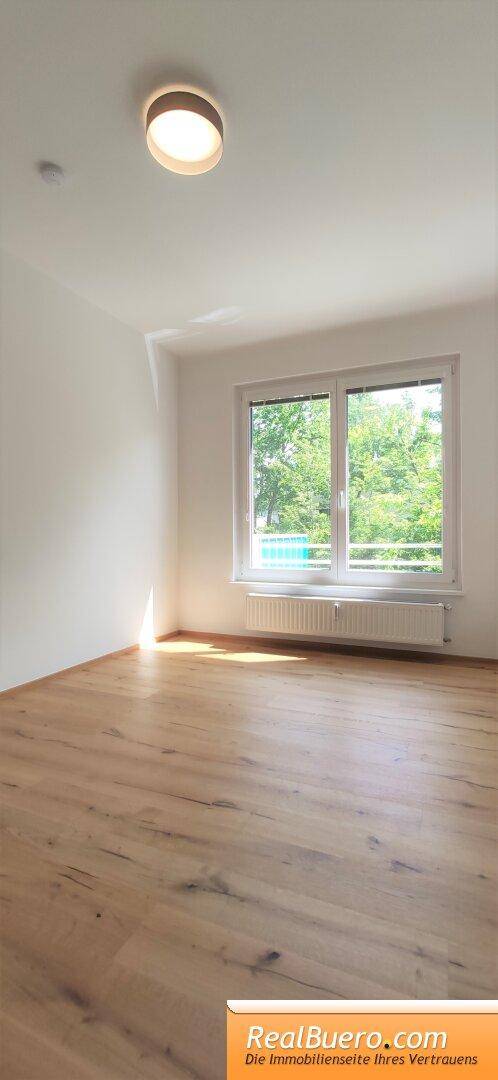 Helles Zimmer mit Holzboden und Fenster, bereit zur individuellen Gestaltung.