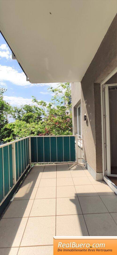 Geräumiger Balkon mit Fliesenboden und Blick ins Grüne, ideal zum Entspannen.