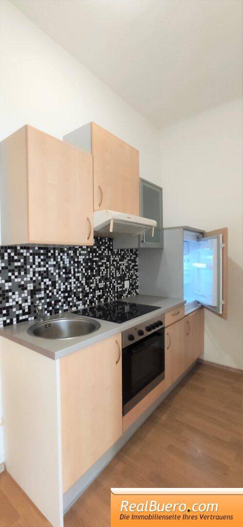 Funktionale Küchenzeile mit Kühlschrank, Herd und Spüle, ausgestattet für den täglichen Gebrauch.
