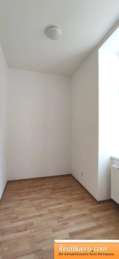 Leeres Zimmer mit Holzboden und einem Fenster, das den Raum hell und freundlich erscheinen lässt.